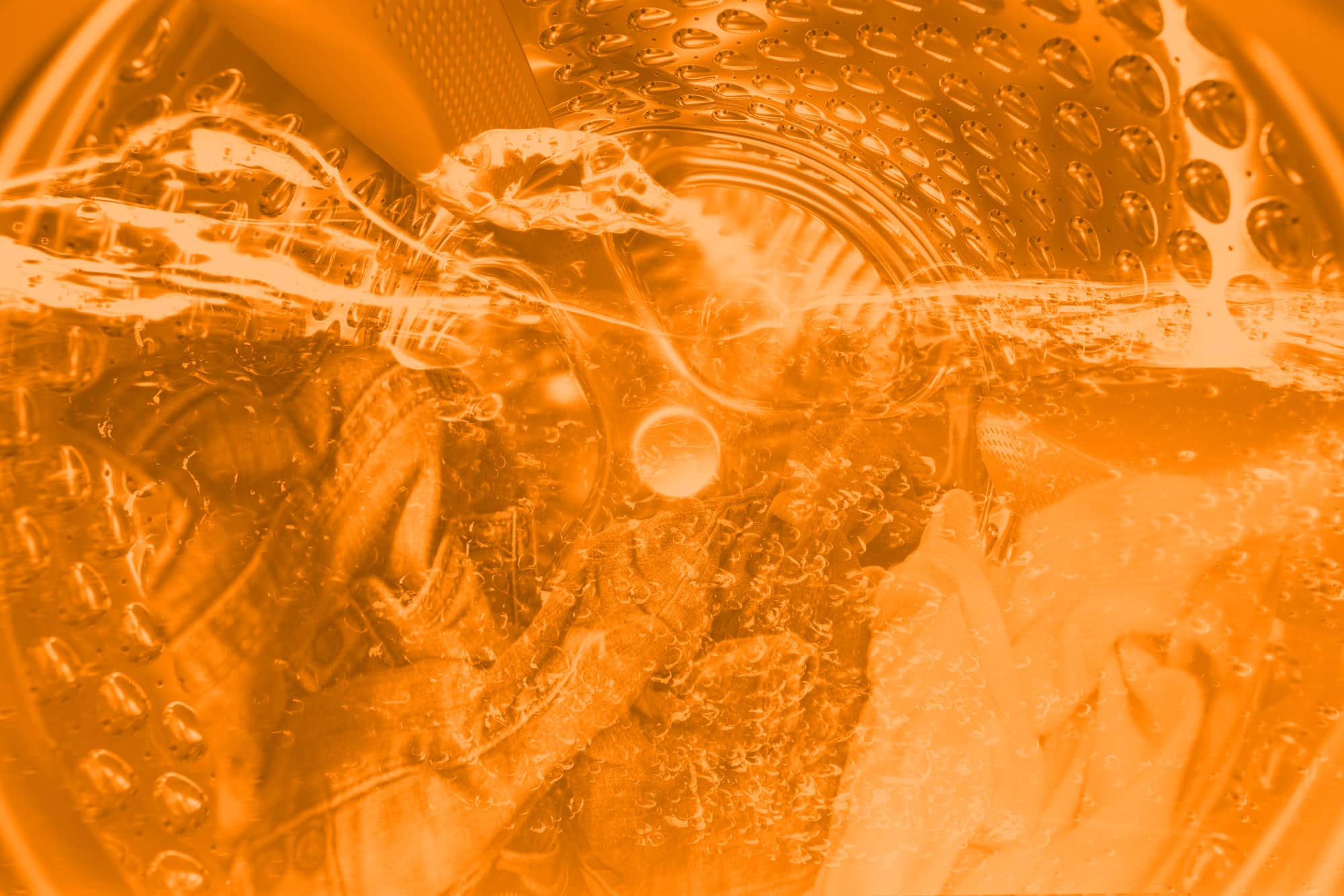 inside of washing machine with water and clothes and orange overlay